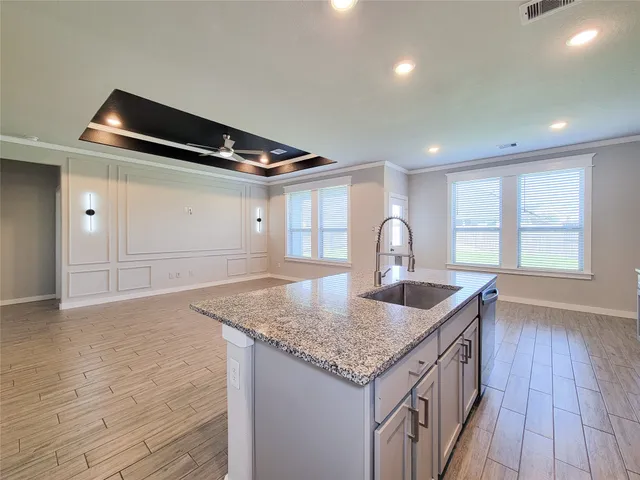a kitchen with granite countertop a sink and a wooden floor