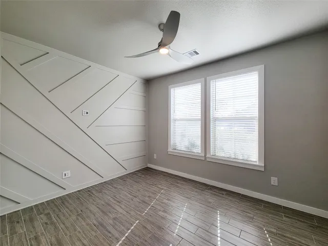 an empty room with wooden floor and windows