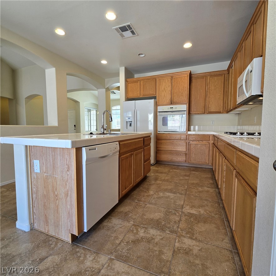 9234 Kingston Road Henderson, NV 89074 - Photo 16 of 38 A well-appointed kitchen features warm wooden cabinetry, a tile island, and ample counter space.