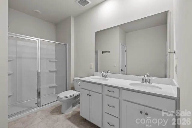 a bathroom with a toilet a sink a mirror and shower