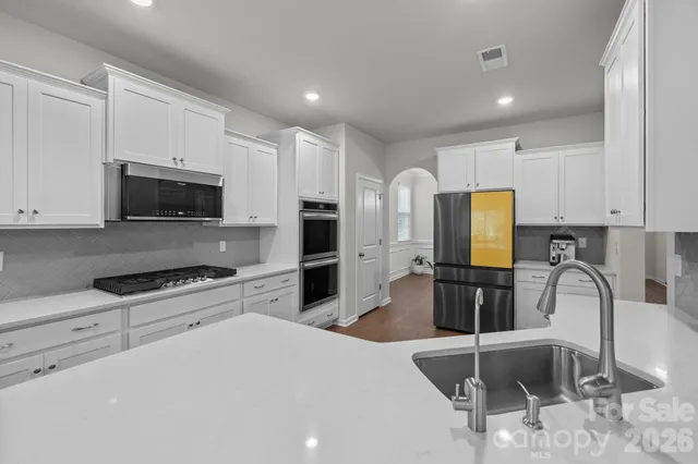 a kitchen with stainless steel appliances a stove a sink a microwave and a refrigerator