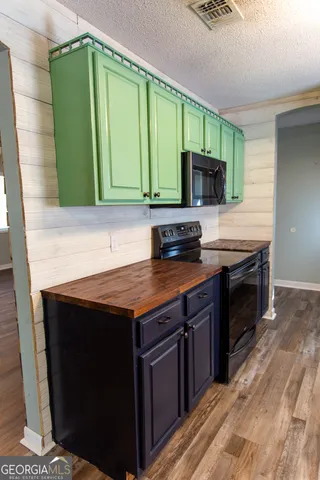 a kitchen with granite countertop a stove top oven microwave and cabinets