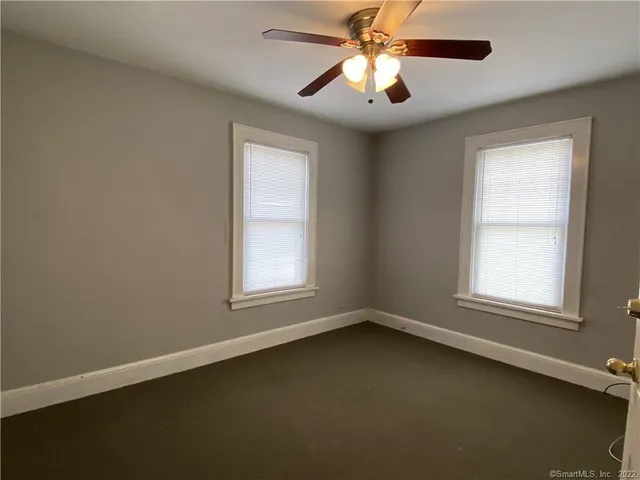 an empty room with a window and a fan