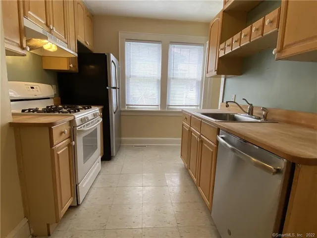 a kitchen with stainless steel appliances granite countertop a stove a sink and a refrigerator
