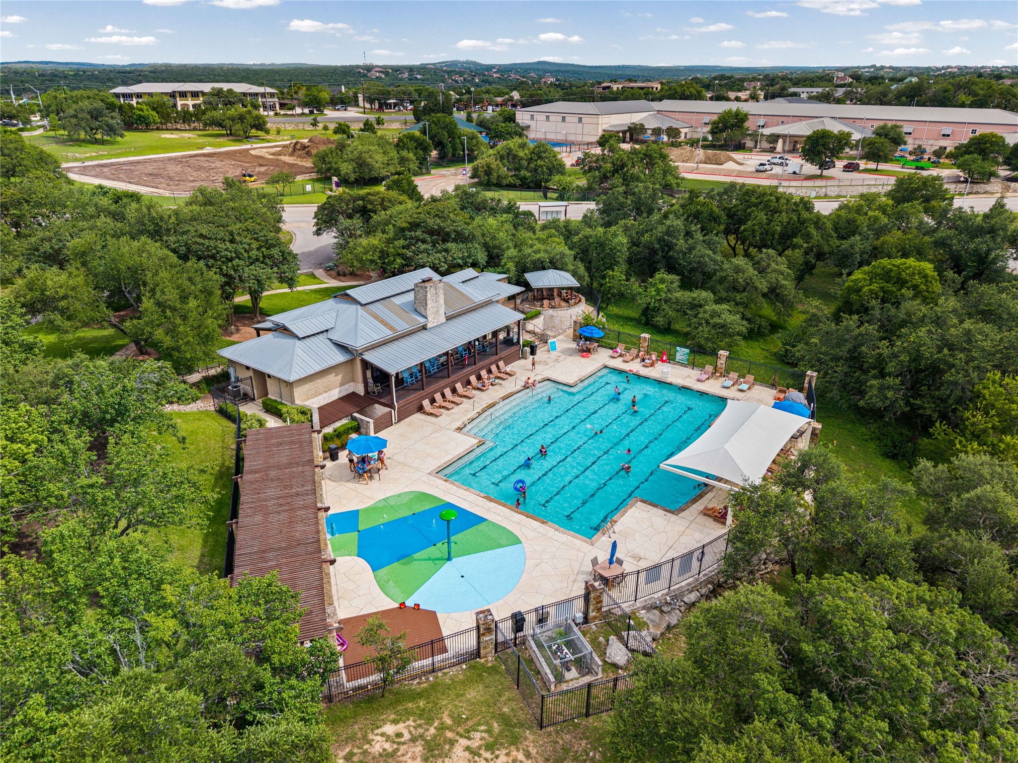 10700 Pointe View Drive Austin, TX 78738 - Photo 30 of 35 An aerial perspective reveals a vibrant community pool with a large swimming area and adjacent splash pad, nestled among mature trees.