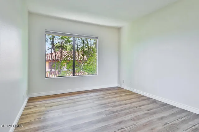 a view of an empty room with wooden floor and closet