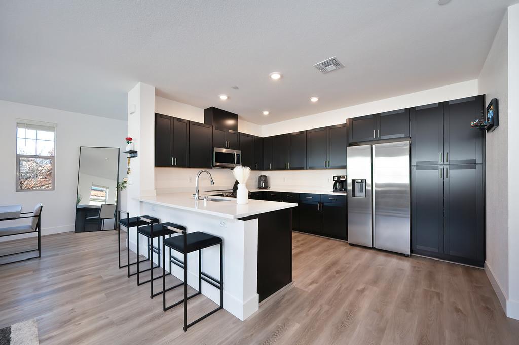 5301 East Commerce Way, Unit 32101 Sacramento, CA 95835 - Photo 20 of 41 a kitchen with stainless steel appliances kitchen island granite countertop a sink a stove a refrigerator and island with wooden floor