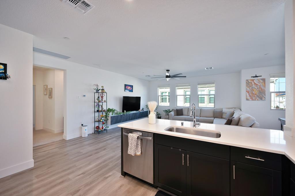 5301 East Commerce Way, Unit 32101 Sacramento, CA 95835 - Photo 25 of 41 a room with stainless steel appliances kitchen island a sink dishwasher a fireplace with wooden floor
