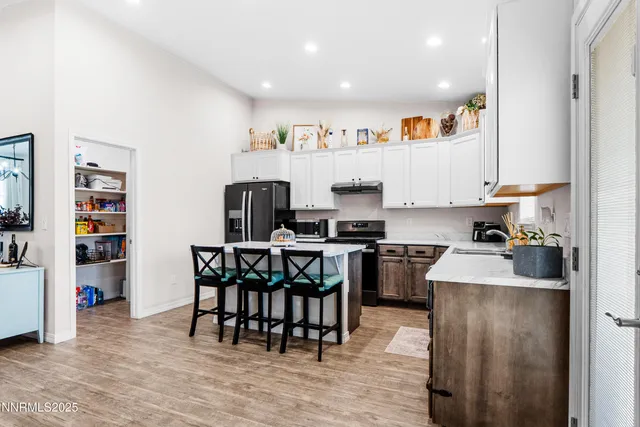 a kitchen with kitchen island granite countertop a refrigerator oven a stove a dining table and chairs with wooden floor