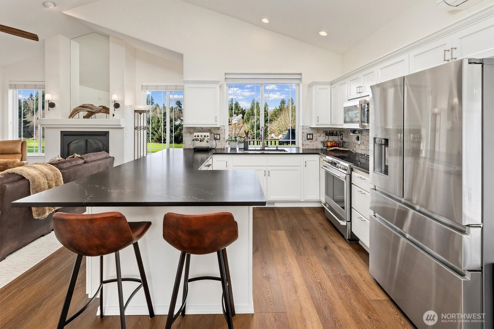 4946 Pleasant Glade Road Northeast Olympia, WA 98516 - Photo 10 of 38 a kitchen with stainless steel appliances granite countertop a refrigerator a stove and white cabinets with wooden floors