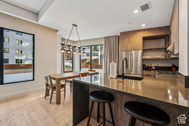 2417 West High Mountain Road, Unit 2202 Park City, UT 84098 - Photo 12 of 28 Kitchen featuring light hardwood / wood-style floors, kitchen peninsula, a breakfast bar, pendant lighting, and high quality fridge