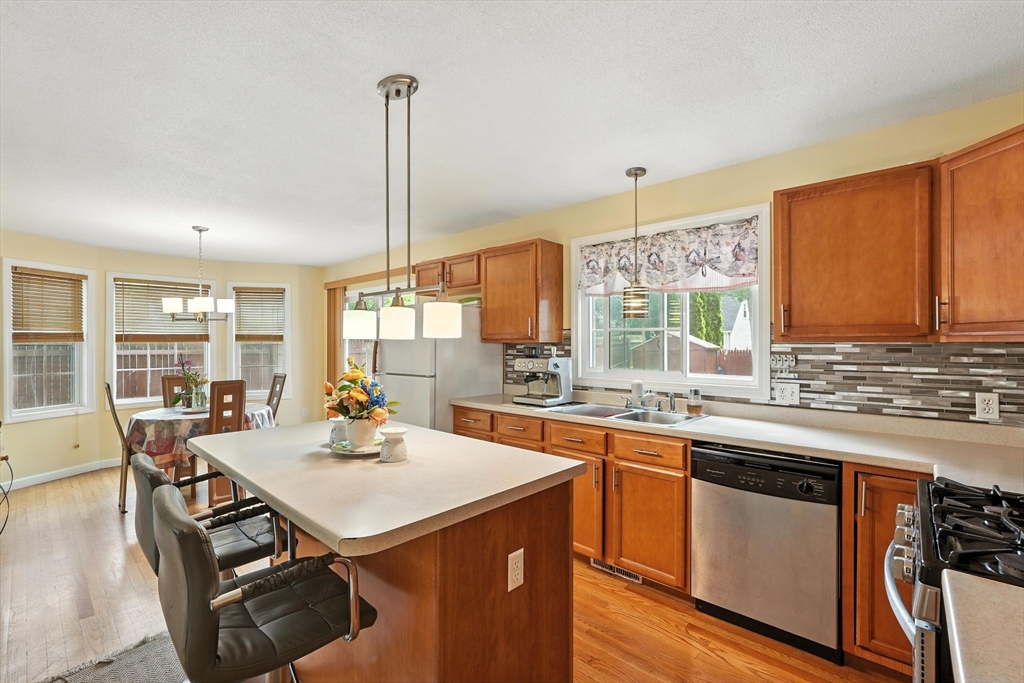 82 Lloyd Avenue Springfield, MA 01119 - Photo 9 of 32 a kitchen with a stove a sink dishwasher a dining table and chairs with wooden floor