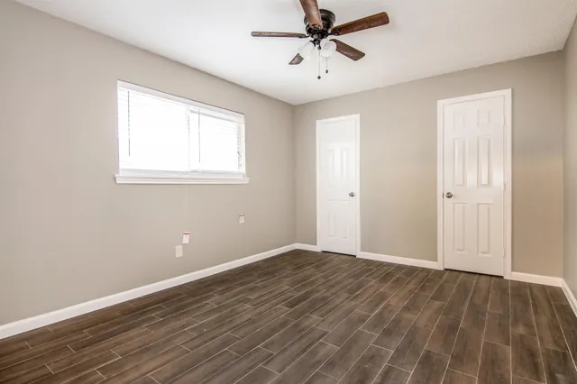 a view of an empty room with wooden floor and a window