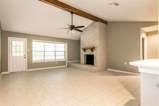 a view of an empty room with a fireplace and a window