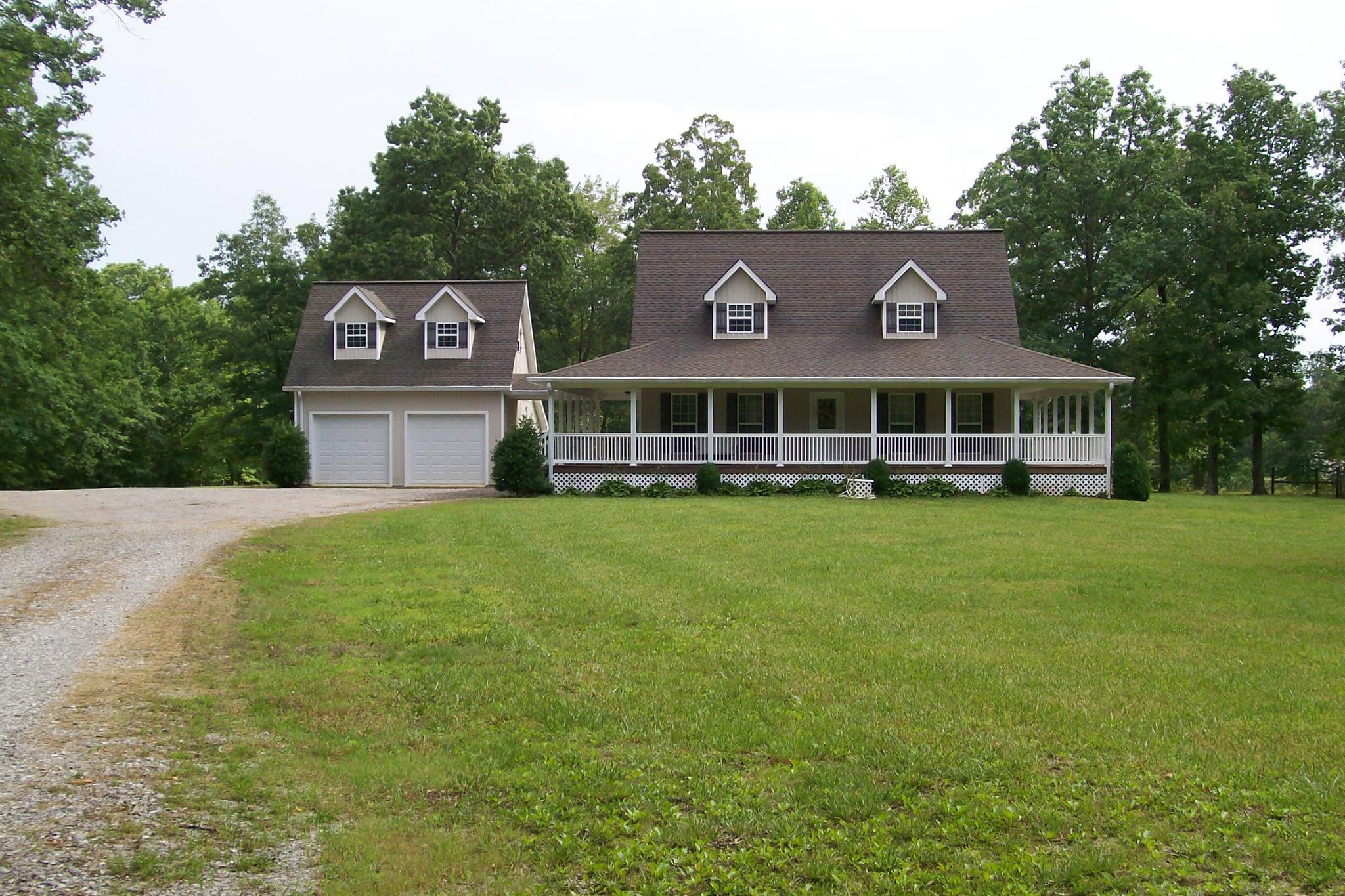 a view of a house with a garden and tall trees