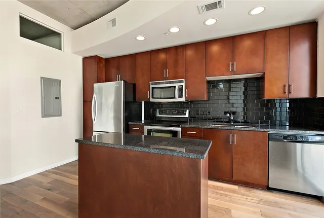 a large kitchen with stainless steel appliances wooden cabinets a stove and a refrigerator