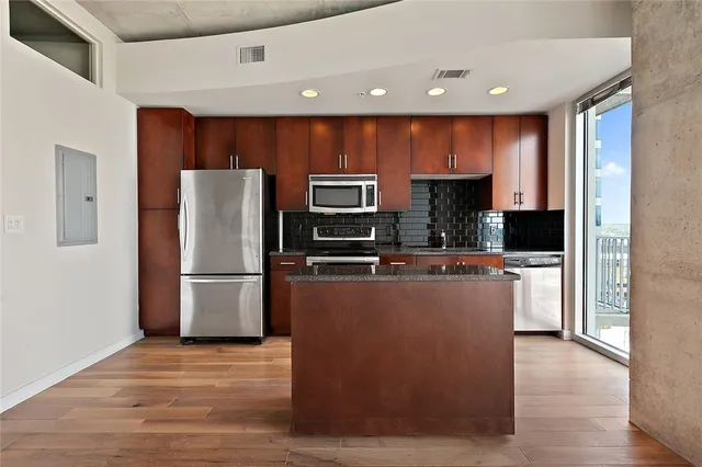 a view of kitchen with stainless steel appliances granite countertop a refrigerator and a stove top oven
