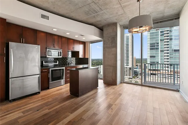 a kitchen with stainless steel appliances a refrigerator and a wooden floor