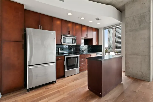 a kitchen with kitchen island wooden cabinets stainless steel appliances and a window