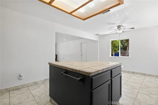 a view of an empty room and kitchen view with wooden floor and a ceiling fan