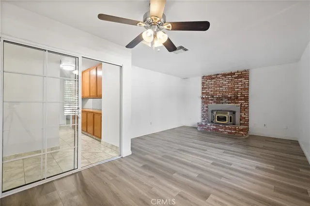 an empty room with wooden floor ceiling fan and windows