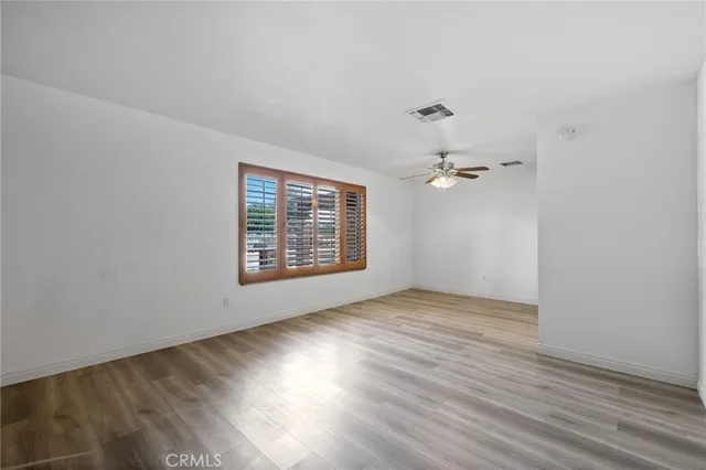 a view of an empty room with a fireplace and a chandelier fan