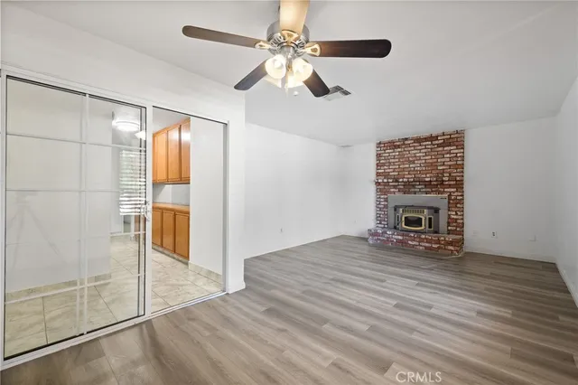 an empty room with wooden floor ceiling fan and windows