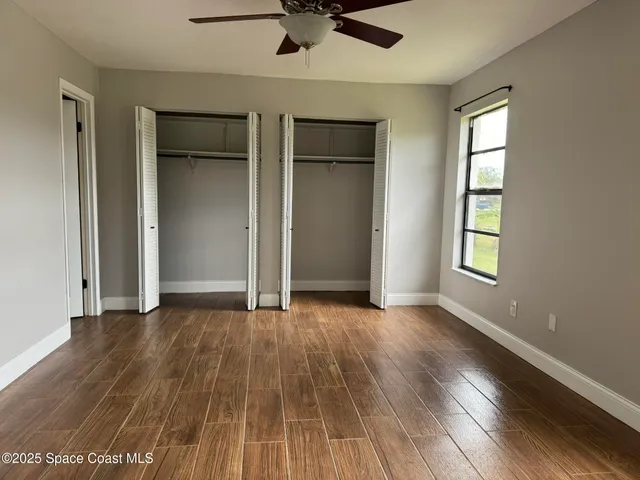 an empty room with wooden floor closet and windows
