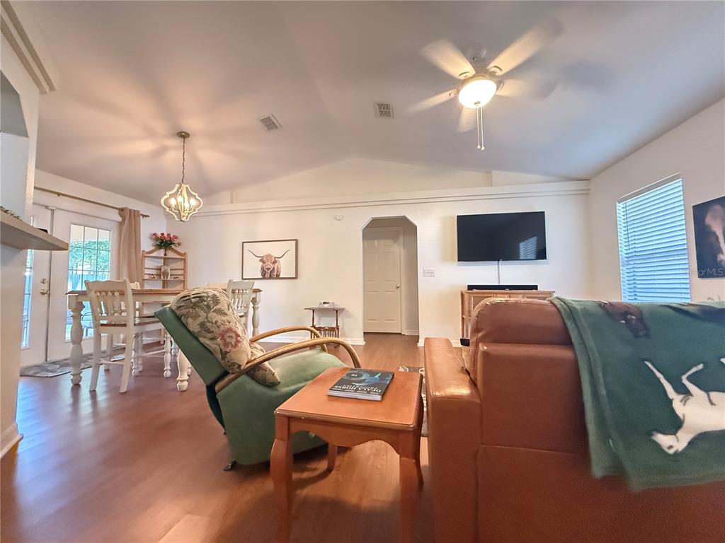 6470 Northwest 56th Terrace Ocala, FL 34482 - Photo 5 of 34 a living room with furniture a chandelier and a flat screen tv