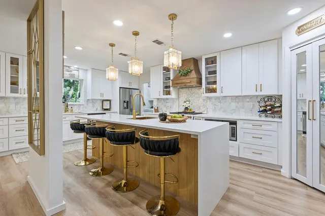 a kitchen with kitchen island granite countertop a table chairs sink and cabinets