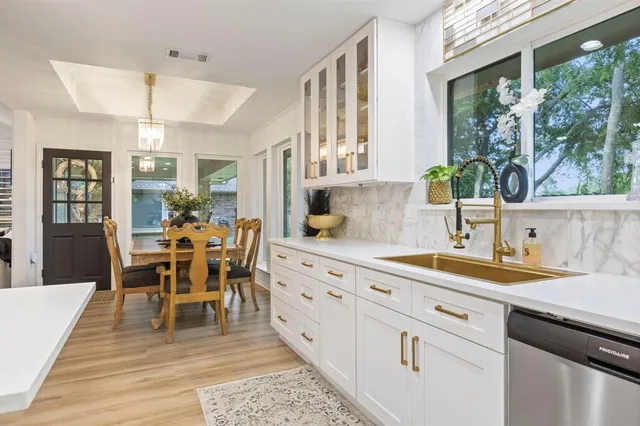 a kitchen with stainless steel appliances kitchen island granite countertop a table chairs sink and cabinets