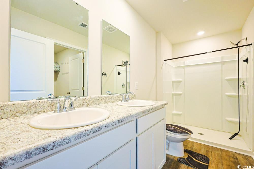 224 Jeff Waters Circle Longs, SC 29568 - Photo 14 of 30 Bathroom with dark wood-style flooring, a shower stall, and double vanity