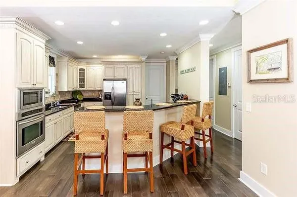 a kitchen with stainless steel appliances granite countertop a stove top oven a sink a dining table and chairs with wooden floor