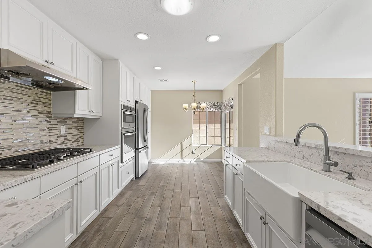 12071 Caminito Corriente San Diego, CA 92128 - Photo 17 of 51 a large kitchen with stainless steel appliances granite countertop a lot of counter space and wooden floors