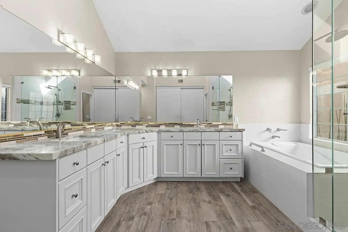 12071 Caminito Corriente San Diego, CA 92128 - Photo 26 of 51 a bathroom with a granite countertop sink a large mirror and a bathtub