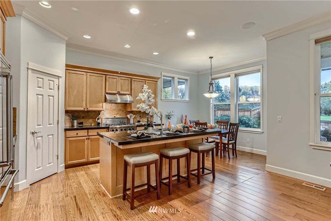 905 South 38th Court Renton, WA 98055 - Photo 12 of 33 a kitchen with stainless steel appliances granite countertop table chairs stove and wooden floor