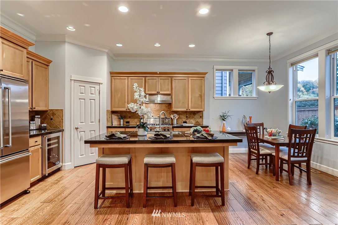 905 South 38th Court Renton, WA 98055 - Photo 13 of 33 a kitchen with stainless steel appliances granite countertop dining table chairs refrigerator and wooden floor