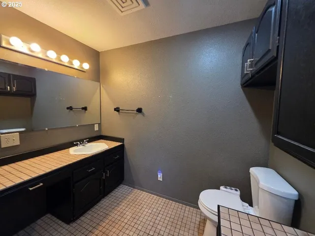 a bathroom with a granite countertop toilet and a sink
