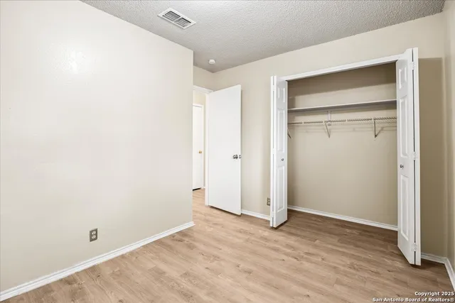 an empty room with wooden floor & closet area