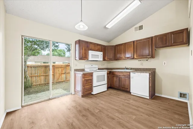 a kitchen with stainless steel appliances granite countertop a stove a sink dishwasher a refrigerator and a microwave oven with wooden floor