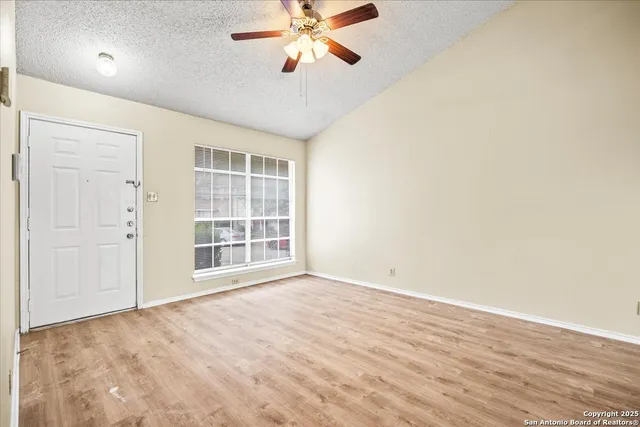 an empty room with windows and fan