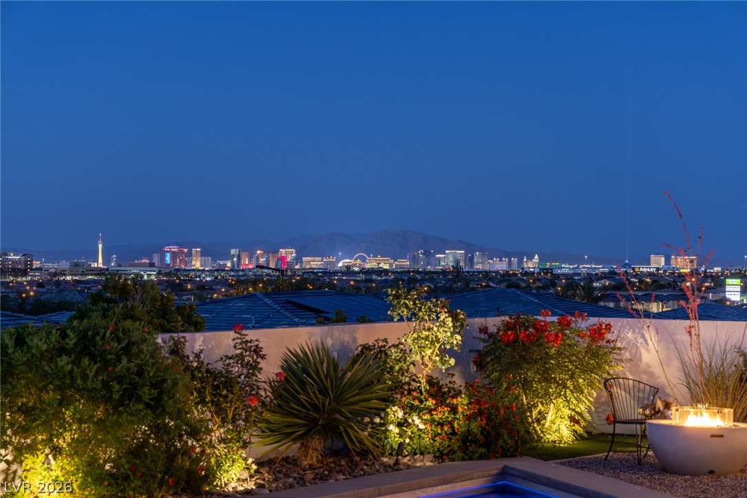 10118 Copper Edge Road Las Vegas, NV 89148 - Photo 32 of 48 City lights glimmer across the horizon from a private, illuminated garden with a cozy fire pit.