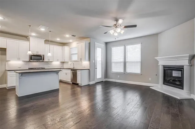 a kitchen with stainless steel appliances granite countertop a stove top oven a refrigerator with white cabinets and wooden floor