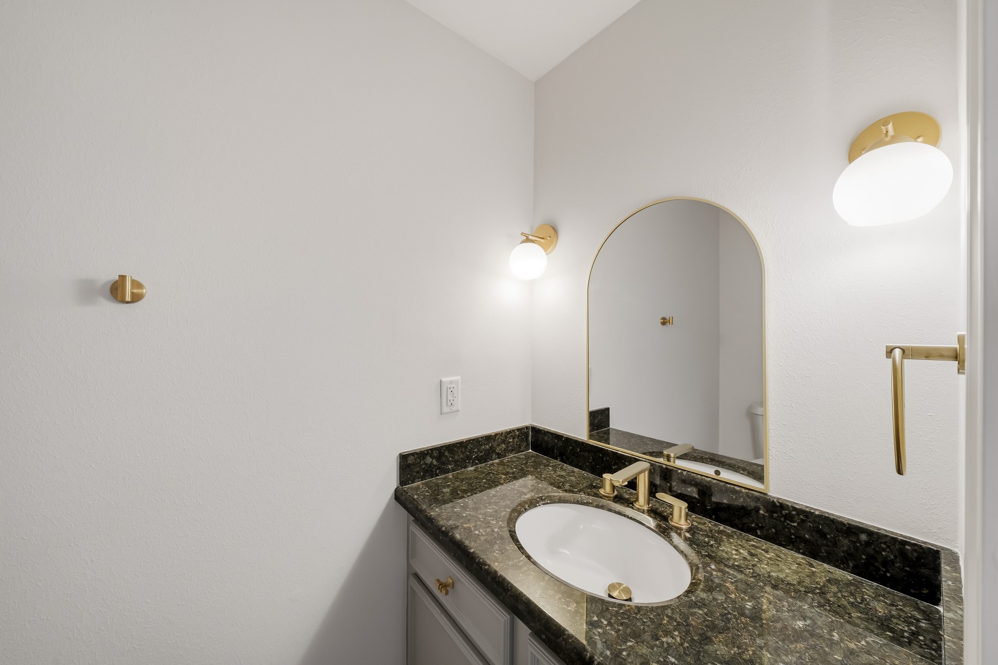 1746 South Gessner Road Houston, TX 77063 - Photo 16 of 25 Elegant bathroom featuring a sleek granite countertop, modern gold fixtures, and a stylish arched mirror with ambient lighting.