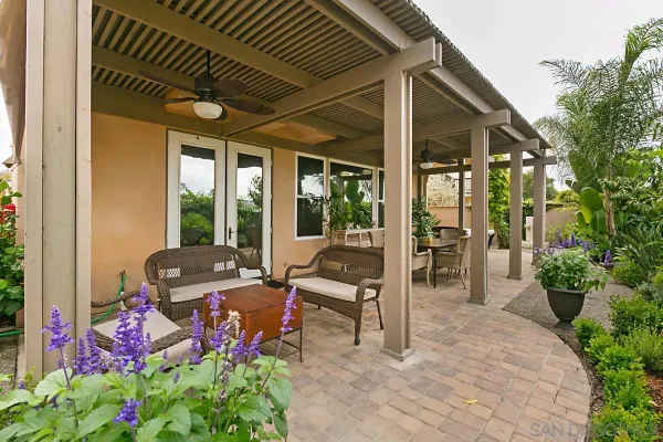 a view of a patio with table and chairs potted plants and floor to ceiling window