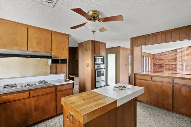 a kitchen that has a kitchen island wooden cabinets and stainless steel appliances