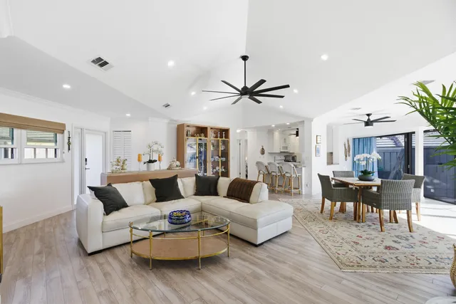 a living room with furniture a clock and a ceiling fan