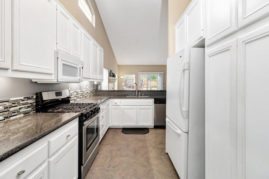 1205 Rancho Pacifica Place Vista, CA 92084 - Photo 13 of 42 a kitchen with granite countertop white cabinets and white appliances