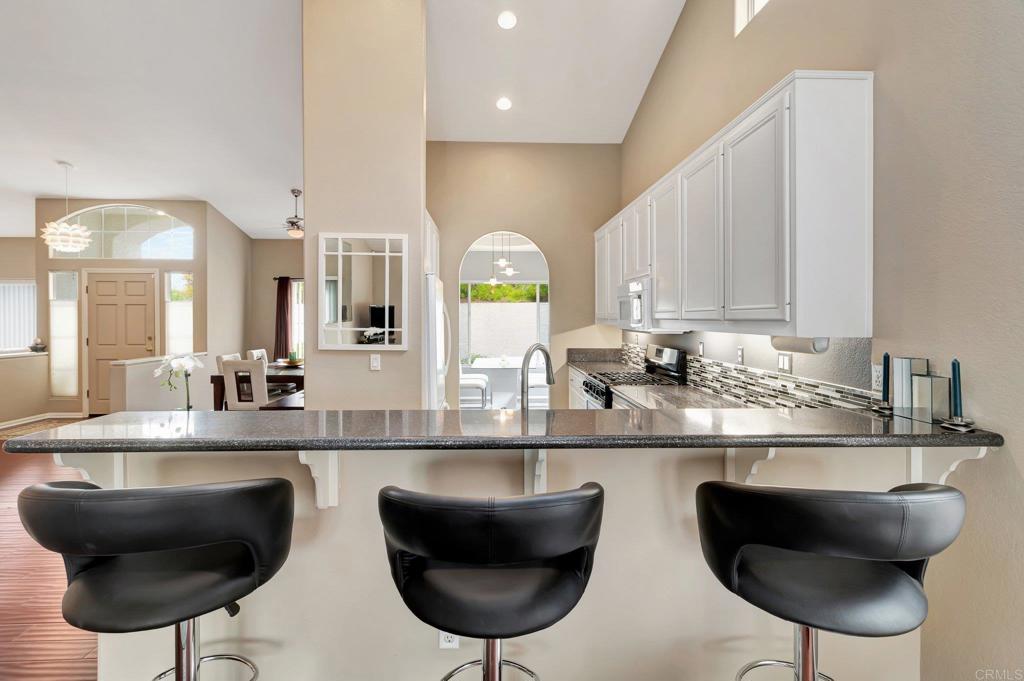 1205 Rancho Pacifica Place Vista, CA 92084 - Photo 15 of 42 a kitchen with stainless steel appliances granite countertop a chairs a stove a kitchen island and chairs in it