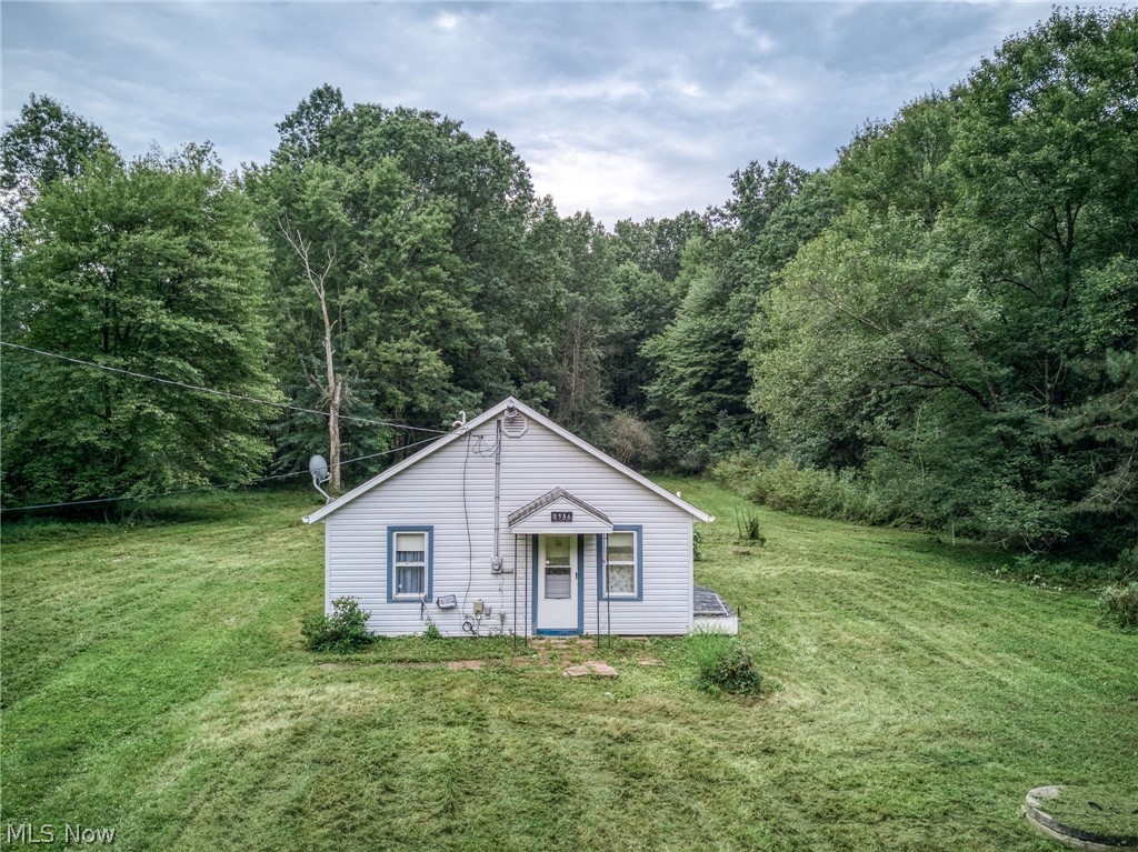 8386 Yale Road Rootstown, OH 44272 - Photo 23 of 46 White siding exterior with blue trim accents, set against a backdrop of mature trees